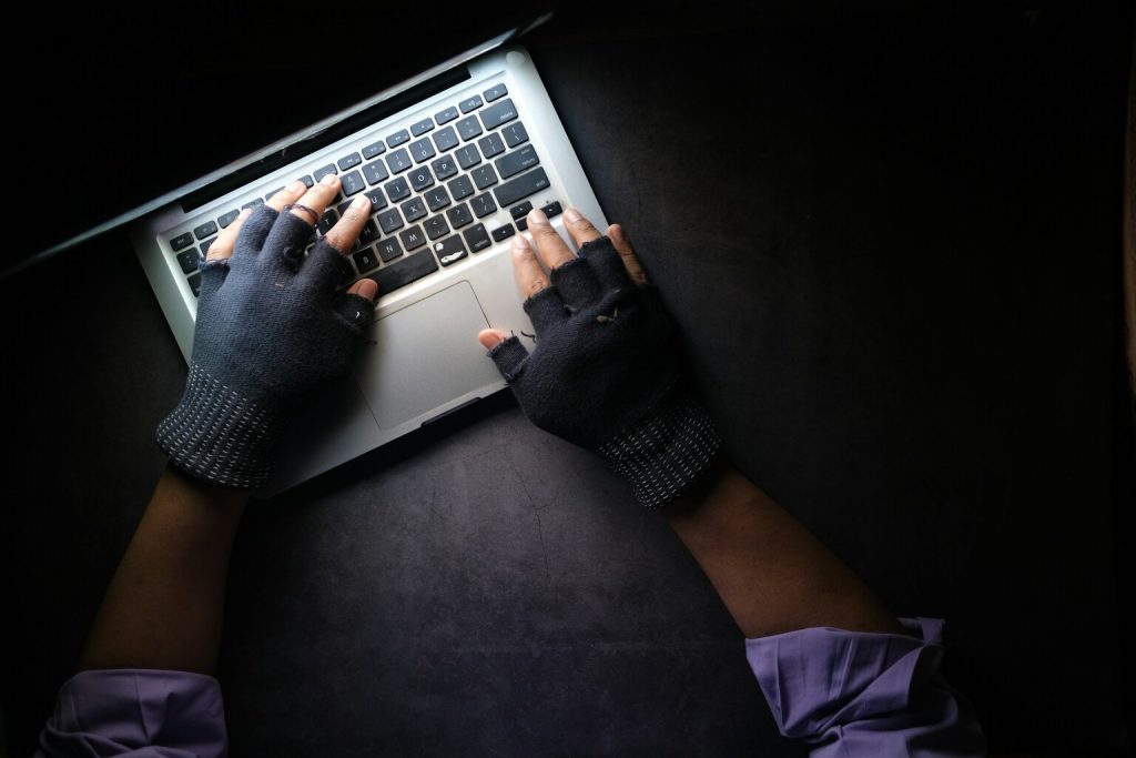 Hacker hands stealing data from laptop top down.