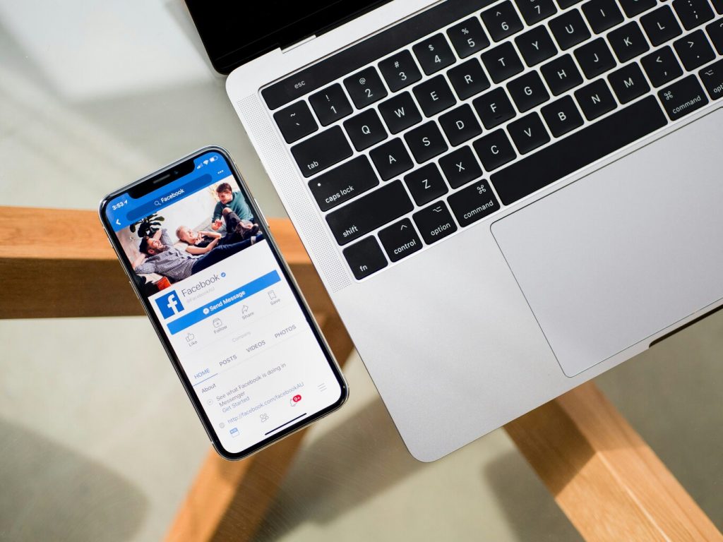 iphone x with Facebook on the screen beside macbook