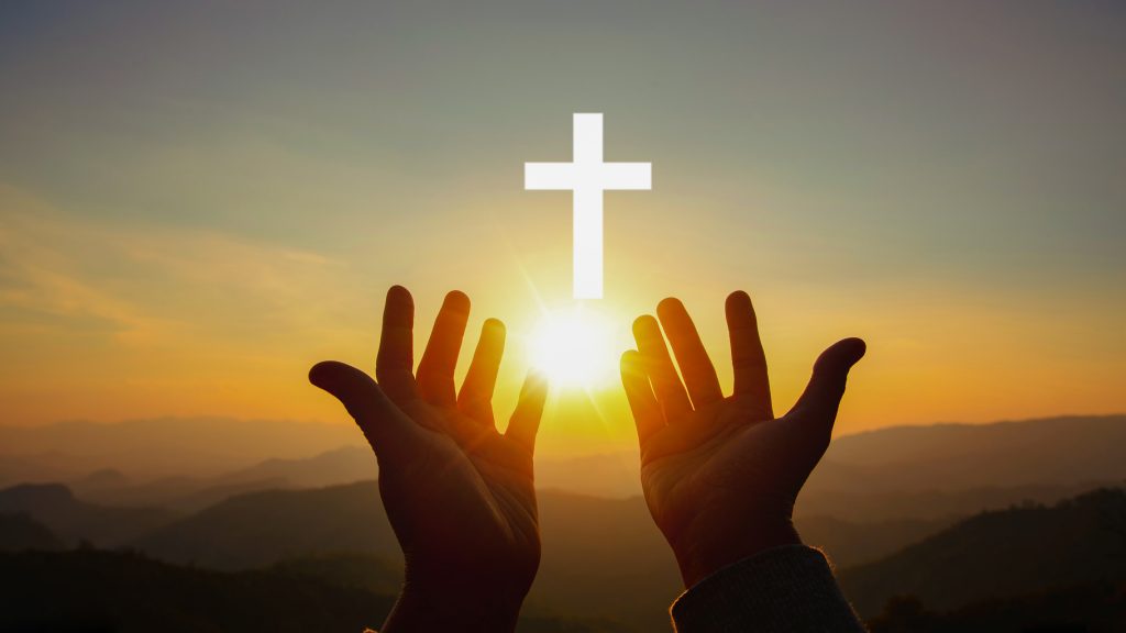 Silhouette of human hands palm up praying and worship of cross