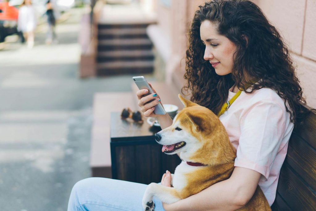 young girl sitting with her dog holding the phone