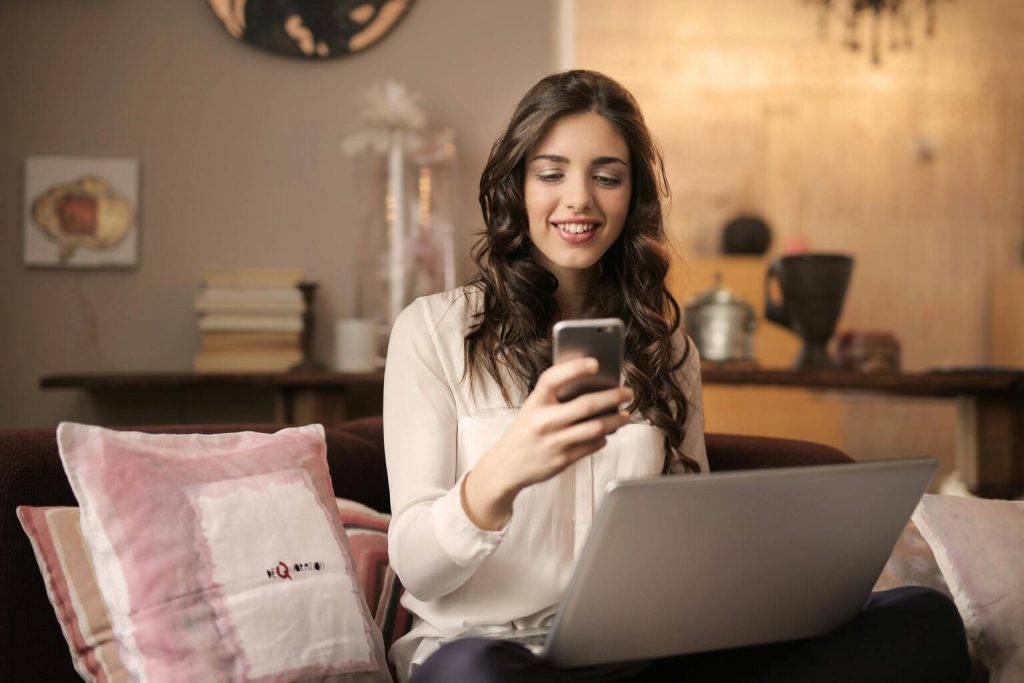 Young woman sitting on the couch at home using mobile phone
