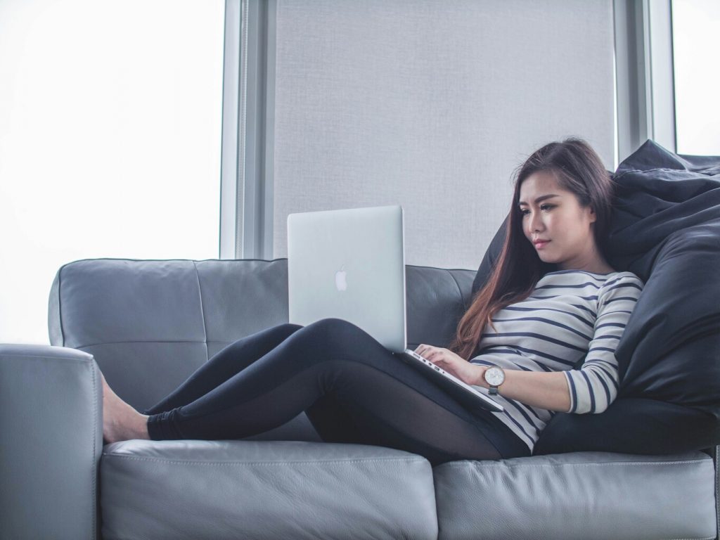 Woman sitting on sofa while using macbook pro.